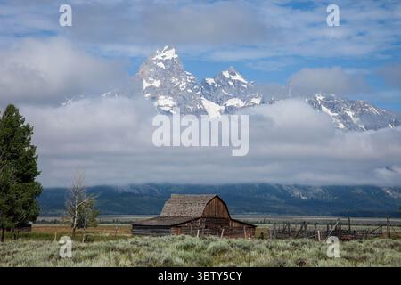 2. August 2011, Grand Teton National Park, Wyoming, Vereinigte Staaten: Die alte Holzscheune auf dem John Moulton Homestead in der Mormon Row im Grand Teton National Park, mit dem Grand Teton aus den Wolken dahinter blickt. Wyoming, USA. (Kreditbild: © Jon G. Fuller/VW Pics via ZUMA Wire) Stockfoto