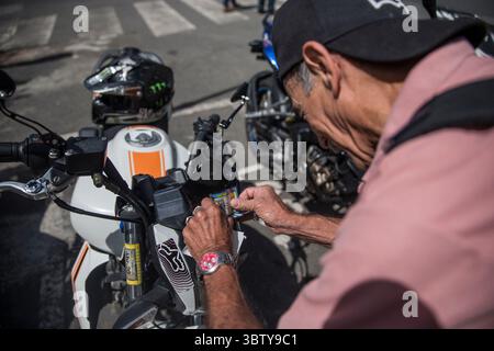 November 2018: 27.11.2018. San JosÃÂ, Costa Rica. INS, visita al Instituto Nacional de Seguros para observar el como va el cobro del Marchamo 2019. EN la Foto: Francisco Badilla Rivera, Le pega el marchamo que acaba de pagar a la Moto. FotografÃÂ­a: Alejandro Gamboa Madrigal (Foto: © Alejandro Gamboa Madrigal/La Nacion Via ZUMA Press) Stockfoto