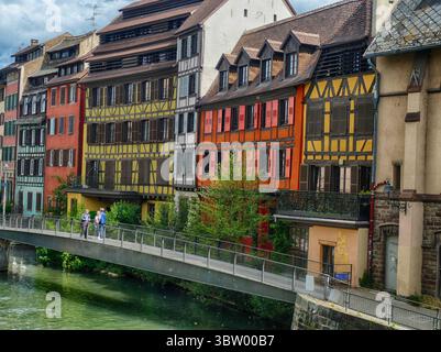 STRASSBURG, FRANKREICH - 27. MAI 2025 - Touristen überqueren die Brücke über den Ill River und sehen die farbenfrohe Fachwerkarchitektur der historischen Petite France Stockfoto