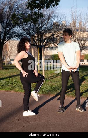 Personal Trainer, der reife Frau beim Beintraining im Park führt Stockfoto