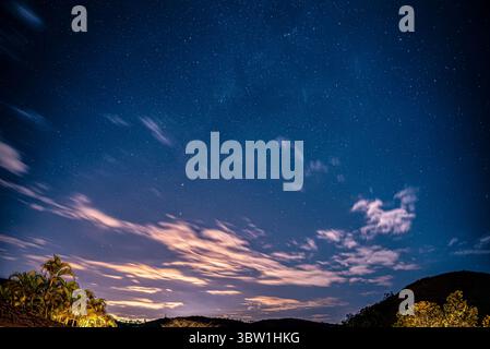 Nachthimmel mit tropischen Silhouetten und leuchtenden Wolken Stockfoto