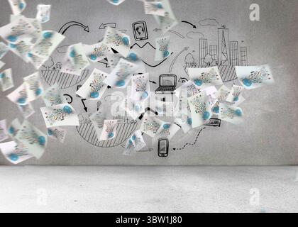 Blätter mit Grafiken vor grauen Wand Stockfoto