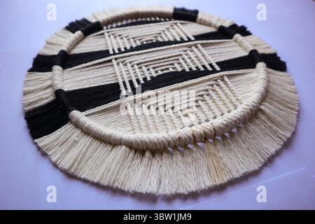 Handgewebte runde Wandaufhängung in Schwarz und weiß. Eine handgefertigte, gewebte Wandkunst in einem auffälligen Schwarz-weiß-Muster Stockfoto