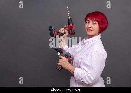 Professionelle Elektrowerkzeuge in Frauenhänden symbolisieren die Gleichstellung der Geschlechter im Bauwesen. Lithium-Ionen-Batterien und kompaktes Design, sichtbar in diesem dy Stockfoto