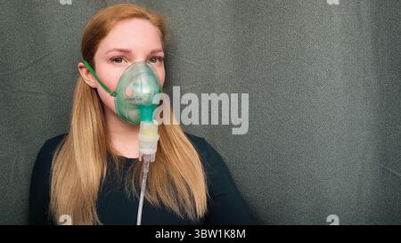 Junge Frau mit Inhalationsmaske in die Kamera blickend mit Hope Atemproblemen und Behandlungskonzept. Hochwertige Fotos Stockfoto