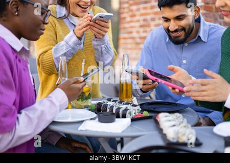 Freunde, die Sushi und Telefone teilen Stockfoto