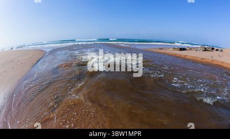 Rivermouth fließendes Wasser mittleres Foto aus der Lagune durch Strand Sandbar zum blauen Himmel Ozean. Stockfoto