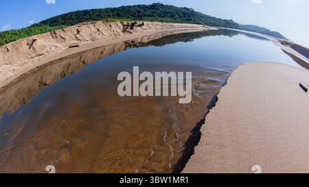 Rivermouth fließendes Wasser mittleres Foto aus der Lagune durch Strand Sandbar zum blauen Himmel Ozean. Stockfoto