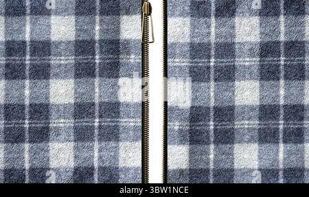 Fleece-Struktur mit Karomuster und offenem Reißverschluss. Reißverschluss oder Verschluss ausgezogen. Offener Reißverschluss und Fleece-Material mit Karomuster in Grau, Stockfoto
