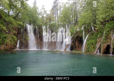 Üppige grüne Vegetation umgibt kaskadierende Wasserfälle im Nationalpark Plitvicer Seen und schafft eine ruhige und unberührte natürliche Landschaft Stockfoto