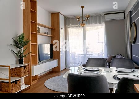 Modernes Interieur mit nahtlosem Wohn- und Essbereich. Elegante Beleuchtung, natürliche Akzente und gemütliche Sitzgelegenheiten schaffen ein einladendes Ambiente Stockfoto