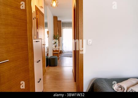 Das moderne Apartment verfügt über einen gemütlichen Flur, der zu einem Schlafzimmer führt, mit warmen Holzelementen und sanfter Beleuchtung für ein einladendes Ambiente. Stockfoto