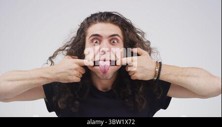 Zunge ausstrecken, dehnen und Porträt des Mannes im Studio für Theaterübungen, Gesichtsübungen und lustiges Gesicht. Aufwärmroutine des Schauspielers, Ausdruck und Stockfoto