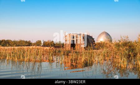 Traditionelle Hütten aus natürlichen Materialien liegen inmitten des Schilfs in den mesopotamischen Sümpfen des Irak und zeigen das lokale Leben. Stockfoto