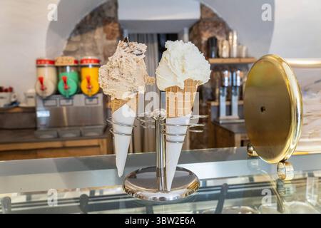 Nago-Torbole, Trentino, Italien - 15. Juli 2025: Zwei große Eiskugeln in einem Kegel in einem Eiscafé in Torbole am Gardasee. Klassische italienische Erfrischung an heißen Sommertagen *** zwei große Kugeln Eis in der Waffel stehen in einer Eisdiele in Torbole am Gardasee. Klassische italienische Erfrischung an heißen Sommertagen Stockfoto