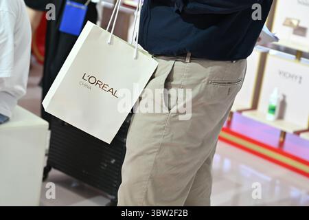 Peking, China. Juli 2025. Ein Mann hält auf der International Supply Chain Fair eine Tasche mit der Aufschrift „L'Oréal China“. L'Oréal ist eines der weltweit größten Kosmetikunternehmen mit starker Präsenz auf dem chinesischen Markt. Quelle: Johannes Neudecker/dpa/Alamy Live News Stockfoto
