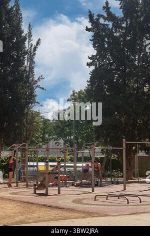 Viladecans. Barcelona - 16. Juli 2025: Menschen, die sich in einem Outdoor-Fitness-Park mit Calisthenics beschäftigen, fördern Gesundheit und Wellness in einer urbanen Umgebung. Stockfoto