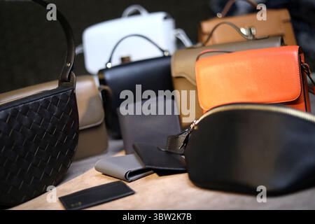 Ein luxuriöses Sortiment an Designer-Handtaschen und Geldbörsen in verschiedenen Stilen und neutralen Tönen. Ein auffälliges orangefarbenes Stück verleiht einen auffälligen Farbakzent Stockfoto