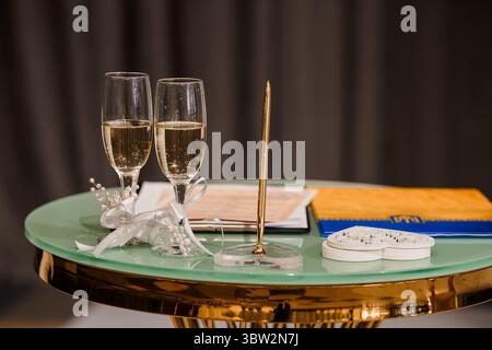 Zwei Sektflöten auf einem Tafel in blaugrün mit goldenen Akzenten, die mit weißen Bändern und Herzen verziert sind, symbolisieren eine romantische Hochzeitsszene, die perfekt für Cell ist Stockfoto