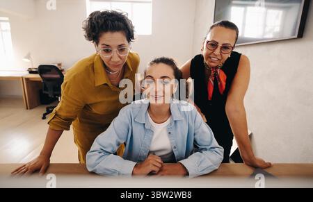 Drei professionelle Frauen arbeiten gemeinsam an einem Projekt in einer modernen und professionellen Büroumgebung. Ihre Diskussion zeigt sich in Stockfoto