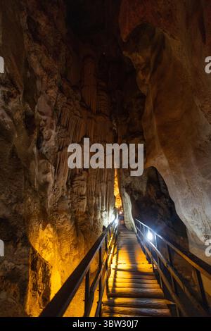 Ein hölzerner Fußweg führt durch eine atemberaubende Höhle, die mit einzigartigen Felsformationen geschmückt ist. Sanfte Lichter beleuchten die atemberaubenden Strukturen der Felsen, cre Stockfoto