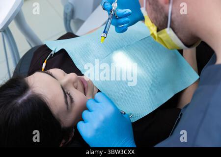 Eine Nahaufnahme einer jungen Frau, die eine Zahnbehandlung in einer modernen Klinik erhält, mit Bürsten und Werkzeugen, die von einem professionellen Zahnarzt in verwendet werden Stockfoto