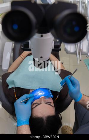 Mikroskopisches Zahnarztverfahren: Nahaufnahme eines Patienten, der mit modernen Instrumenten und fachärztlicher Betreuung in einer modernen Zahnarztpraxis behandelt wird Stockfoto