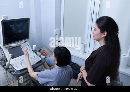 Medizinische Ultraschalluntersuchung im Gange bei pflegenden Angehörigen der Gesundheitsberufe und einem Patienten, der sich einem diagnostischen Verfahren in einem modernen Gesundheitswesen unterzieht Stockfoto