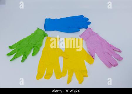 Eine lebendige Kollektion von bunten Gummihandschuhen, die ordentlich auf einer weißen Oberfläche angeordnet sind und eine Mischung aus Farben für verschiedene Reinigungs- und Schutzzwecke bieten Stockfoto