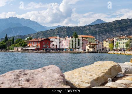 Torbole, Gardasee, Italien - 15. Juli 2025: Eine bunte Häuserreihe direkt am Ufer: Das malerische Torbole am Gardasee verzaubert mit seinem mediterranen Flair, charmanten Gassen und Blick auf die Alpen. Ein beliebter Ort für Spaziergänge, Eis und Wassersport. *** Bunte Häuserzeile direkt am Ufer: Das malerische Torbole am Gardasee verzaubert mit mediterranem Flair, charmanten Gassen und Alpenblick. Ein beliebter Ort für Spaziergänge, Gelato und Wassersport. Stockfoto