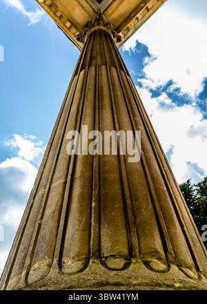Ein Niedrigwinkelaufnahme einer kannelierten Säule vor einem blauen Himmel mit Wolken. Stockfoto
