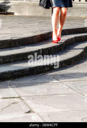 Eine Person, die rote High Heels trägt, läuft eine Treppe hinunter. Stockfoto