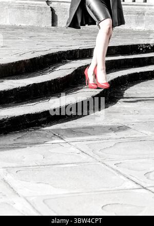 Eine Person, die rote High Heels trägt, läuft eine Steintreppe hinunter. Stockfoto