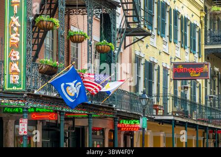Flaggen, Musikklubs und Restaurantneonschilder in einer Straße im French Quarter, New Orleans, Louisiana Stockfoto