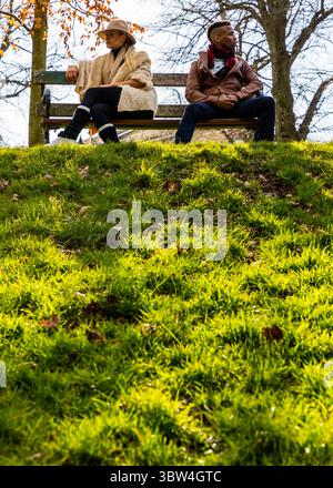 Ein Mann und eine Frau sitzen auf einer Bank im Park. Stockfoto