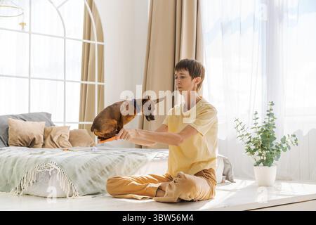 Besitzer spielt mit fröhlichem Hund zu Hause, glückliche reife Frau genießt Sport Stockfoto