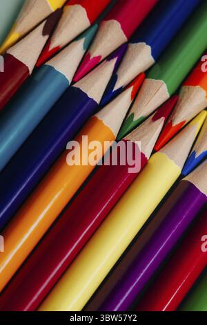 Farbige, geschärfte Bleistifte liegen in Nahaufnahme in einer Reihe. Solider abstrakter Hintergrund von mehrfarbigen Holzstiften. Das sind Schulmaterialien Stockfoto