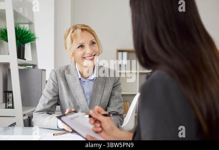 Zwei Geschäftsfrauen diskutieren Projektaufgaben am Schreibtisch und arbeiten am Arbeitstag im Büro zusammen. Stockfoto