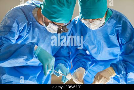 Zwei ausgebildete professionelle Chirurgen, die eine Operation im modernen Operationssaal des Krankenhauses durchführen. Stockfoto