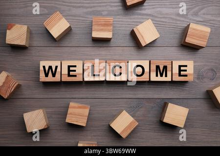 Wort Willkommen aus Holzwürfeln auf dem Tisch, flach gelegen Stockfoto