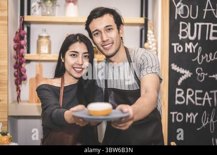 Junge Paare, die Bäckerei Krapfen und Brot in der Bäckerei als Besitz von Unternehmen Unternehmer. Mann und Frau zusammen kochen in der Küche. Happines Stockfoto