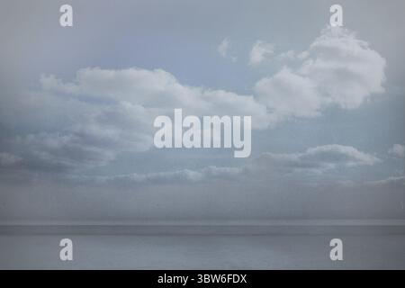 Meereswasser plätschert sanft über die Horizontlinie unter weichen Cumuluswolken in flacher Form Stockfoto