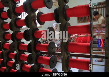 Rollen mit rotem Garn sind in einer lokalen Textilindustrie, die noch manuell arbeitet, ordentlich angeordnet. Stockfoto