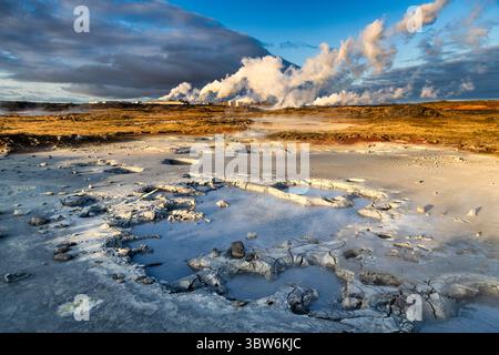 Blick auf die geothermische Gegend mit sprudelnden Schlammbecken, dampfenden Lüftungsöffnungen und kontrastfarbenen Farben unter einem dynamischen Himmel, Hverir, Island. Stockfoto