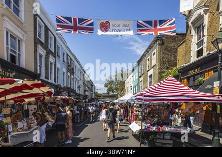 Erleben Sie den lebhaften Charme des Portobello Road Market in London, bekannt für seine einzigartigen Verkaufsstände, britischen Flaggen und lebhaften Straßen. London, Großbritannien, 25. Juni Stockfoto