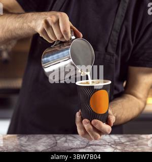 Männlicher Barista, der Kaffee zubereitet. Latte Art aus nächster Nähe machen Stockfoto