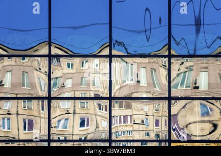 Krumme Reflexion von Häusern im Glas des Fensters abstrakt farbiger Hintergrund Stockfoto