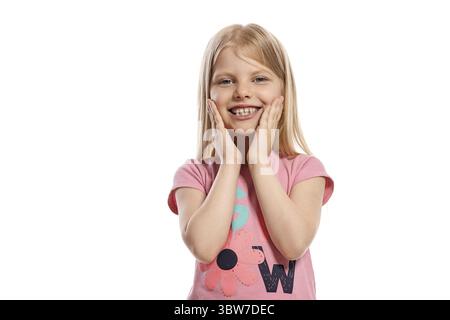 Nahaufnahme eines schönen blonden Kindes mit langen Haaren in einem rosa T-Shirt, das glücklich und lächelnd aussieht, während er isoliert auf weißem Hintergrund posiert Stockfoto