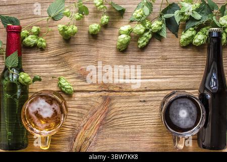 Flasche und ein Glas helles und dunkles Bier mit Hopfen und Kopierbereich auf hölzernem Hintergrund. Draufsicht. Flache Lagen. Stillleben Stockfoto