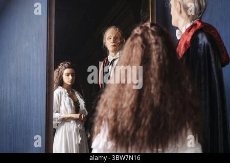 Schönes Mädchen in weißem Kleid und gruseliger entstellter Mann in schwarzem Stand Stockfoto